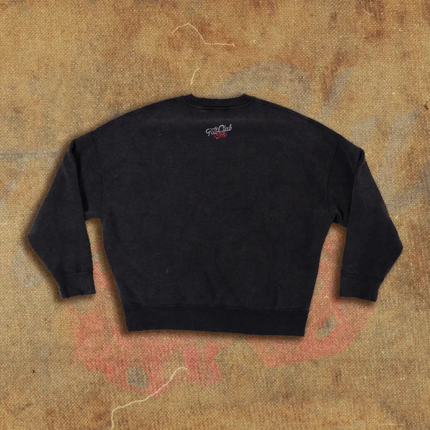 Black crewneck sweatshirt featuring a small 'Tilt Club' logo with dice graphics on the upper back. Minimalist design ideal for casual wear.