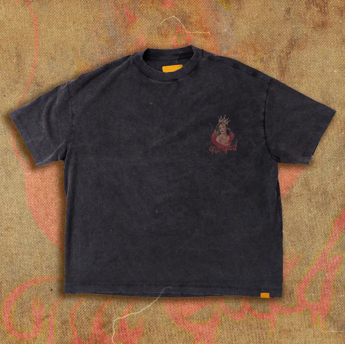 Back view of a black t-shirt featuring a large graphic of a crowned devil girl with red flames and the Tilt Club logo in fiery script, displayed on a textured, flame-inspired backdrop.